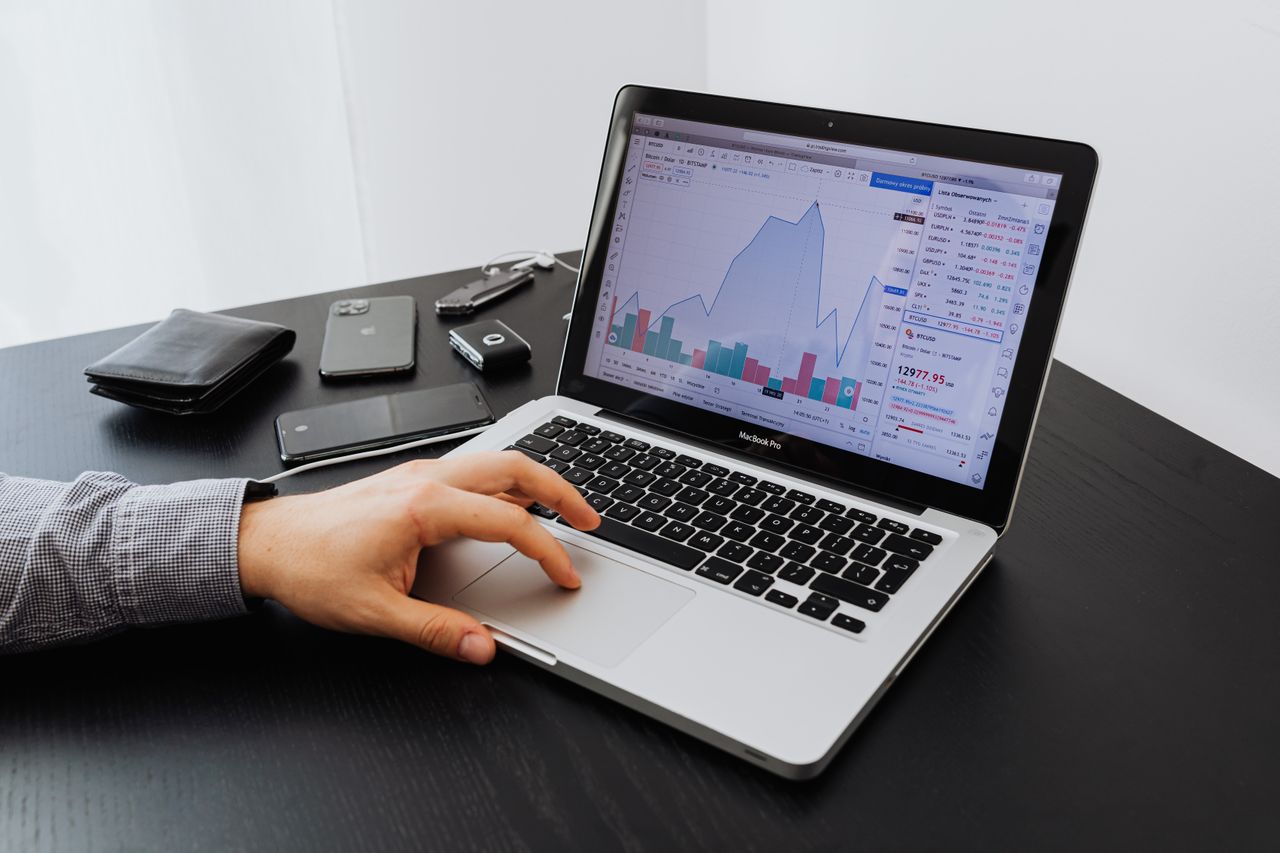 Services Person analyzing stock market data on a laptop at a desk.